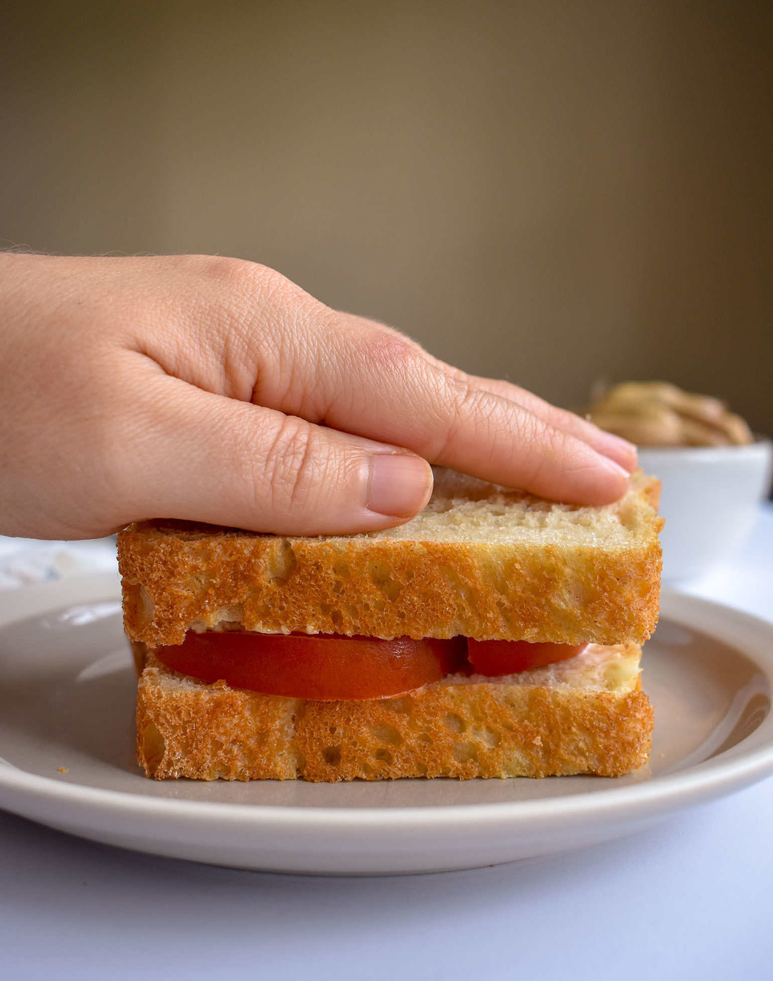 Tomato and mayo sandwich being put together